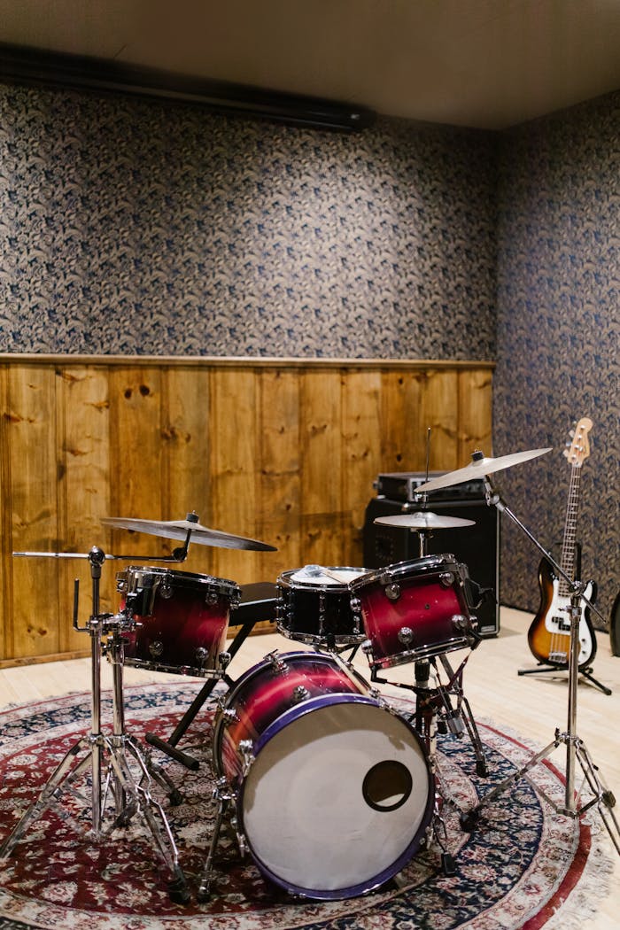 Vibrant drum set in a cozy studio with wooden and patterned walls. Ideal for music enthusiasts.